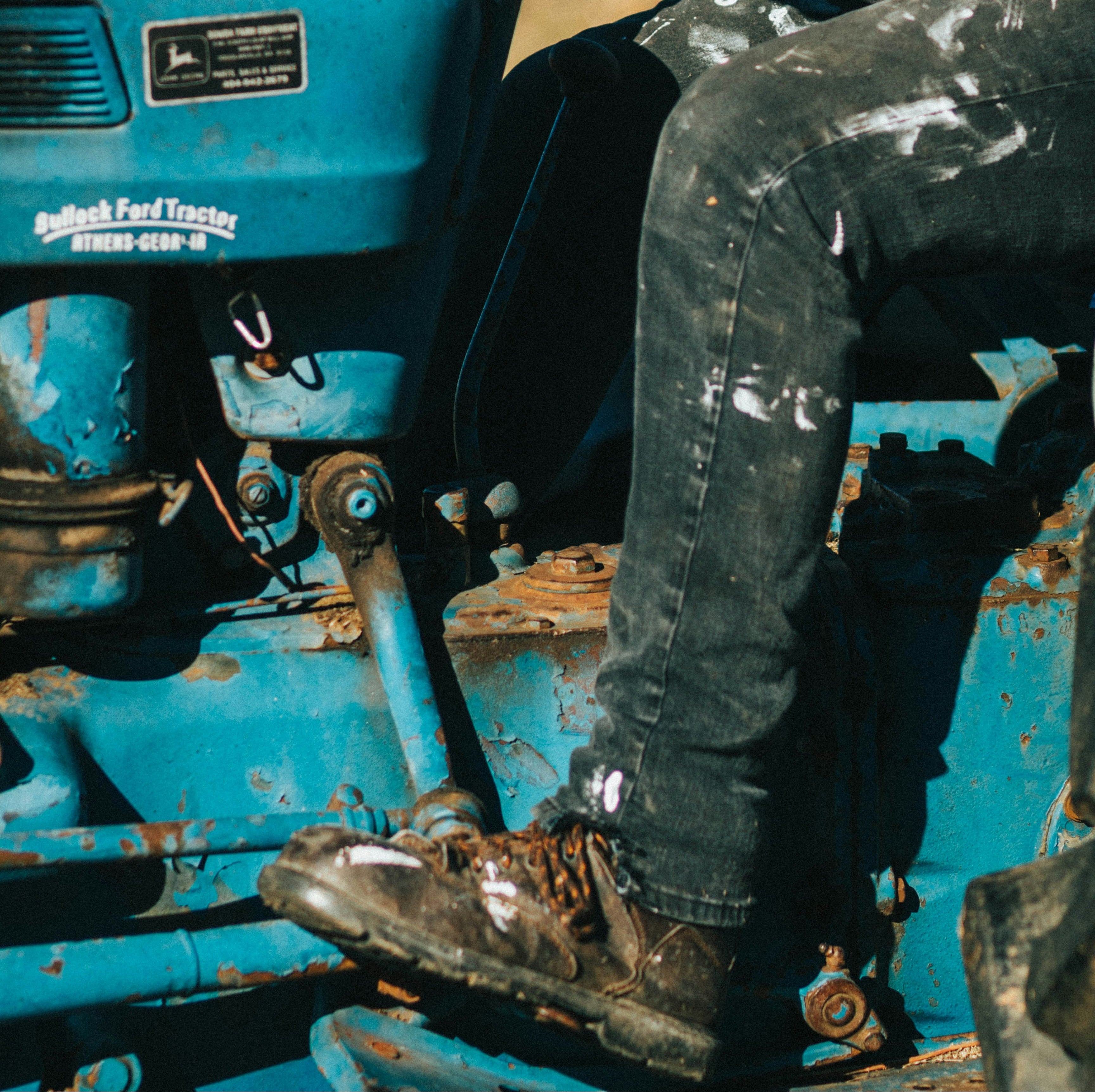Person sitting on a blue tractor with a blurred natural background